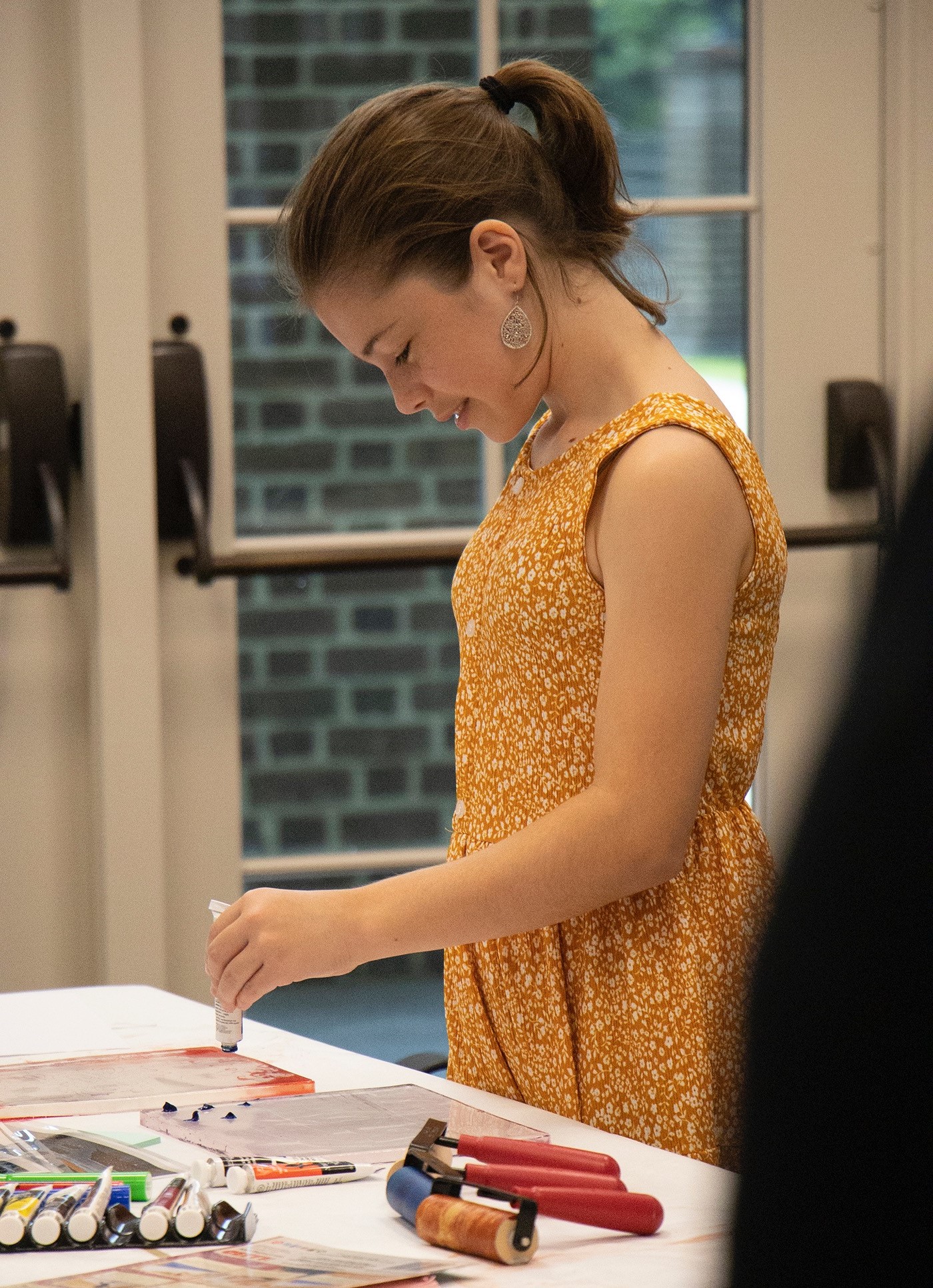 A teen standing at a table, creating artwork